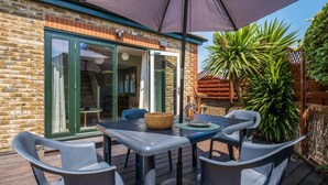 A patio with a table and chairs, a basket, and a potted plant. - Garden apartment with parking in Rye (Rye)