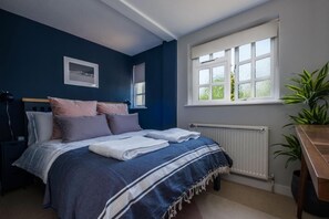 Une chambre avec un lit, une fenêtre, un radiateur et une plante.