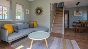 A living room with a sofa, a round table, a staircase, and a dining area. - Garden apartment with parking in Rye (Rye)