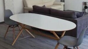 Un salon moderne avec une table ronde, un canapé et une étagère fixée au mur.