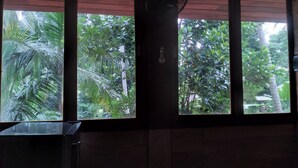 A room with large windows, a ceiling fan, and a view of lush greenery outside. - Green Herbal Ayurvedic Eco-Chalets  (Unawatuna)