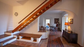 Een trap die leidt naar een tweede verdieping, een eethoek met een tafel en stoelen, en een kamerbreed tapijt op de vloer.