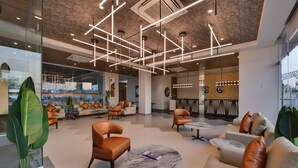 A modern lobby with leather sofas, a marble coffee table, and geometric ceiling lights. - Click Hotel Pithampur (Dr. Ambedkar Nagar)