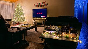 A cozy living room with a Christmas tree, a flat-screen TV, and a bookshelf. - Let our place be the basecamp for your exploration at Yosemite! (Mariposa)