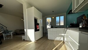 Una cuina moderna amb armaris blancs, una illa central i una zona de dinar amb taula i cadires.
