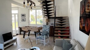 Un saló modern amb una taula de futbolí, un sofà, una taula de centre i una escala amb un disseny únic.