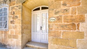 A stone building with a white door and a sign reading "Ta'Karma". - Karmnu - Ghasri Holiday Home (L-Għasri)