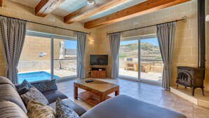 A living room with a sofa, coffee table, TV, and a fireplace. - Rebekah – Ghasri Holiday Home (L-Għasri)