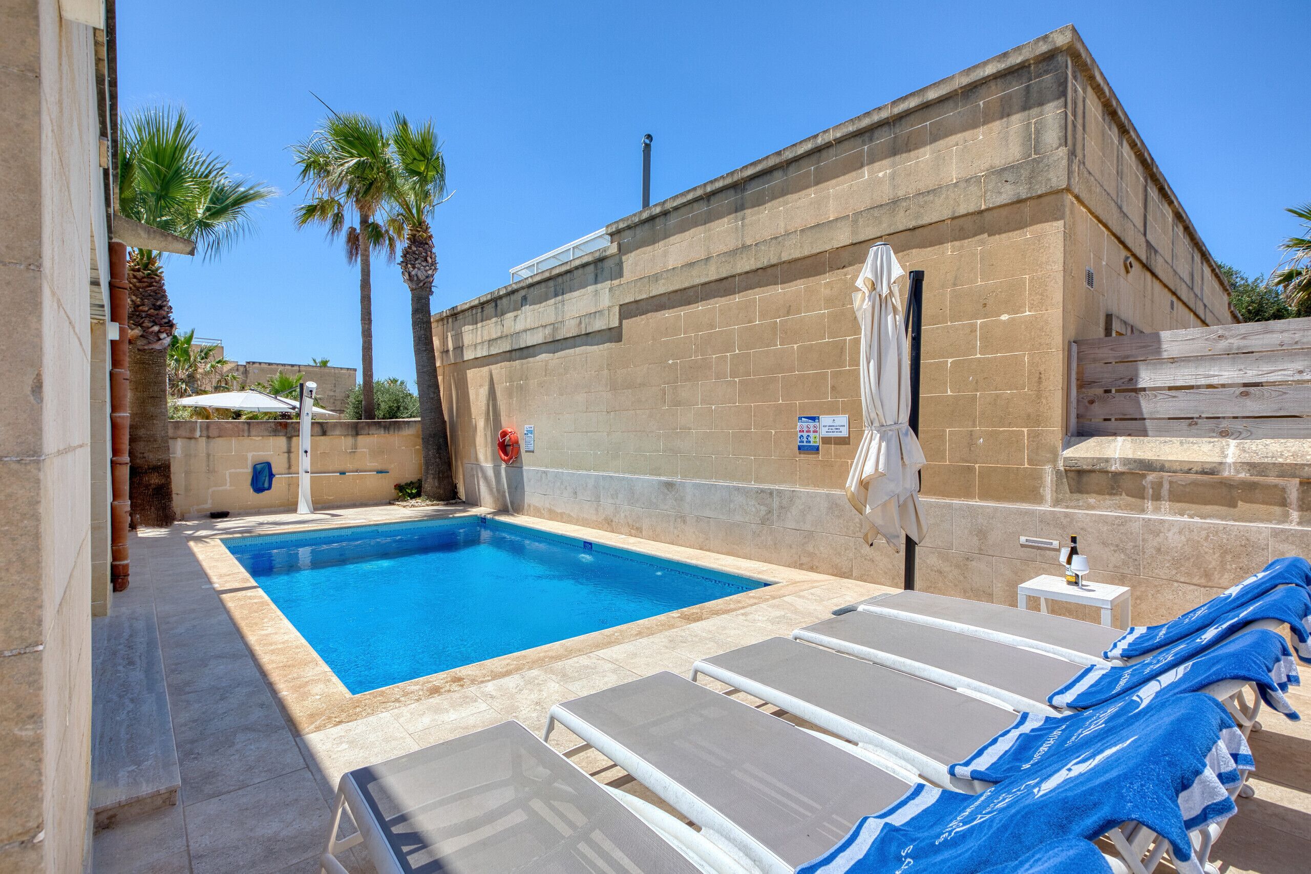 Une piscine avec des chaises longues et un mur en briques.