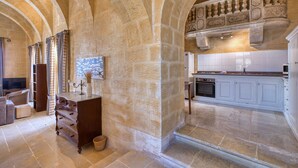 A spacious interior with stone arches, a kitchen with white cabinets, and a fireplace. - Gharilma IV – Santa Lucija Holiday Home (Ta' Kerċem)