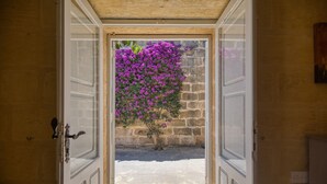An open doorway leading to a courtyard with a stone wall and a flowering bush. - Gharilma IV – Santa Lucija Holiday Home (Ta' Kerċem)