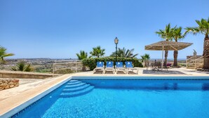 A swimming pool with lounge chairs and a view of the landscape. - Gharilma IV – Santa Lucija Holiday Home (Ta' Kerċem)