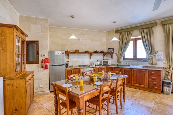 A kitchen with a central island, wooden cabinets, a refrigerator, and a dining table set for four.