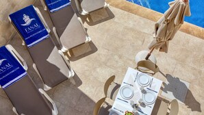 Un espace repas aménagé au bord de la piscine, avec des chaises longues et une table dressée pour le repas.