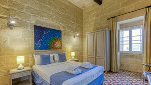 A bedroom with a bed, nightstands, a wardrobe, a window with curtains, and a colorful wall art piece. - Girardu - Victoria Holiday Home (Victoria)