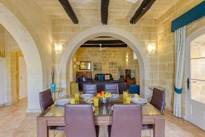 A dining area with a stone wall, a wooden ceiling, and a central seating arrangement.