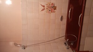 Un baño con azulejos blancos, una ducha con puerta de cristal y un armario de madera.