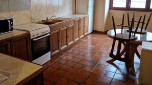 Una cocina con protector contra salpicaduras de piedra, armarios de madera, estufa, microondas, fregadero y comedor con mesa y sillas.