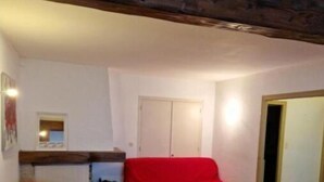 Un salón acogedor con techo de madera, un sofá rojo, un armario blanco y una mesita pequeña.