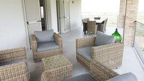 A covered patio area with wicker furniture and a green vase. - Cascina Canelli - Apt. Alba, Cascina Canelli - Apt. Alba (Canelli)