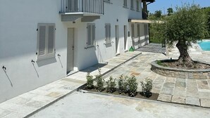 Um edifício de dois andares com paredes brancas, persianas e uma varanda.