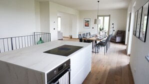 Uma cozinha moderna com bancada de mármore, forno embutido e área de refeições com mesa e cadeiras de madeira.