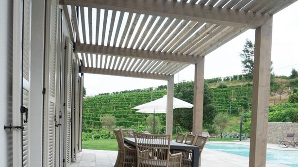 Área externa coberta com piscina, móveis de exterior e duas garrafas verdes no chão.
