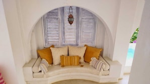 A cozy seating area with a cushioned bench, a patterned rug, and a decorative hanging lantern. - Casablanca Oasis (Troncones)