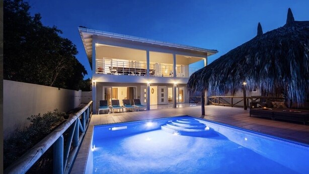 Ein modernes, zweistöckiges Haus mit einem Schwimmbecken im Vordergrund.