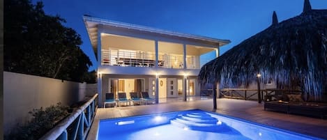A modern two-story house with a swimming pool in the foreground.