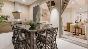 A modern kitchen with a dining area, featuring a grill, a large window, and a cozy living room with a sofa and decorative plants. - Near Disney/No Resort fee/Entire House/Free Parking Wi-Fi/Shared Heated Pool (Kissimmee)