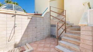 Un baño con ducha, inodoro y lavamanos. Una escalera conduce a un nivel superior.