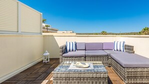 Terraza en la azotea con un conjunto de sofás de mimbre, una mesita con un adorno y un farol blanco.