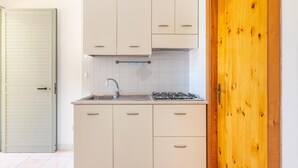 Una cocina con armarios blancos, un fregadero y una estufa.