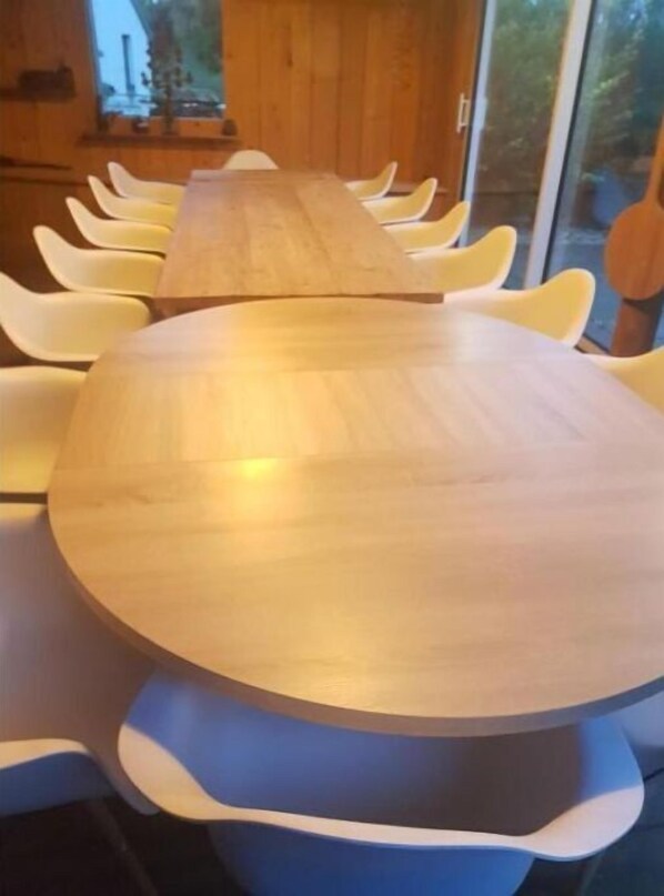 A long wooden table with white chairs, set in a room with large windows and a wooden interior. - Grande Demeure D'exception (Clairvaux-les-Lacs)