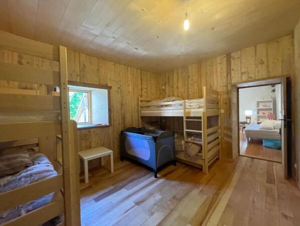 A wooden room with bunk beds, a small table, and a window.