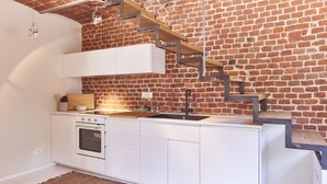 A compact kitchen with white cabinetry, a built-in oven, and a wooden countertop. - AQVAE Unconventional Country House (Piemonte)