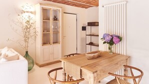 A cozy dining area with a wooden table and wicker chairs, a cabinet with glass doors, and a radiator. - AQVAE Unconventional Country House (Piemonte)