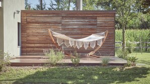 A hammock on a wooden deck with a modern building in the background. - AQVAE Unconventional Country House (Piemonte)