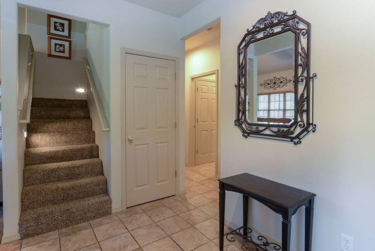 A hallway with a carpeted staircase, a white door, and a wall-mounted mirror.