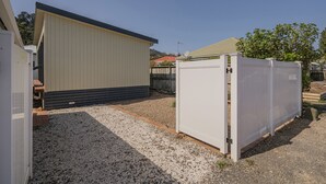 Un quartier résidentiel avec un grand hangar, une cour clôturée et une maison en arrière-plan.