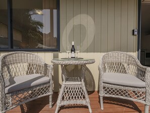 A wicker outdoor seating area with two chairs and a small table, a bottle of wine, and a glass on the table. - Gold'n Thames - Thames Holiday Home (Thames)