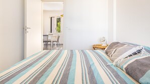 A bedroom with a bed, a bedside table with a lamp, and a view of a dining area through an open door. - 3590 Charà by Barbarhouse (Ugento)