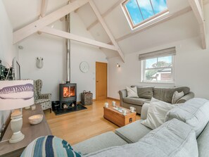 Amplia sala de estar con techo alto, chimenea, sofá, mesa de centro y ventana con vistas.