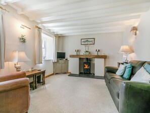 A living room with a fireplace, a sofa, a television, and a lamp. - 4 bedroom accommodation in St Just-in-Roseland, near St Mawes (St Just-in-Roseland, near St Mawes)