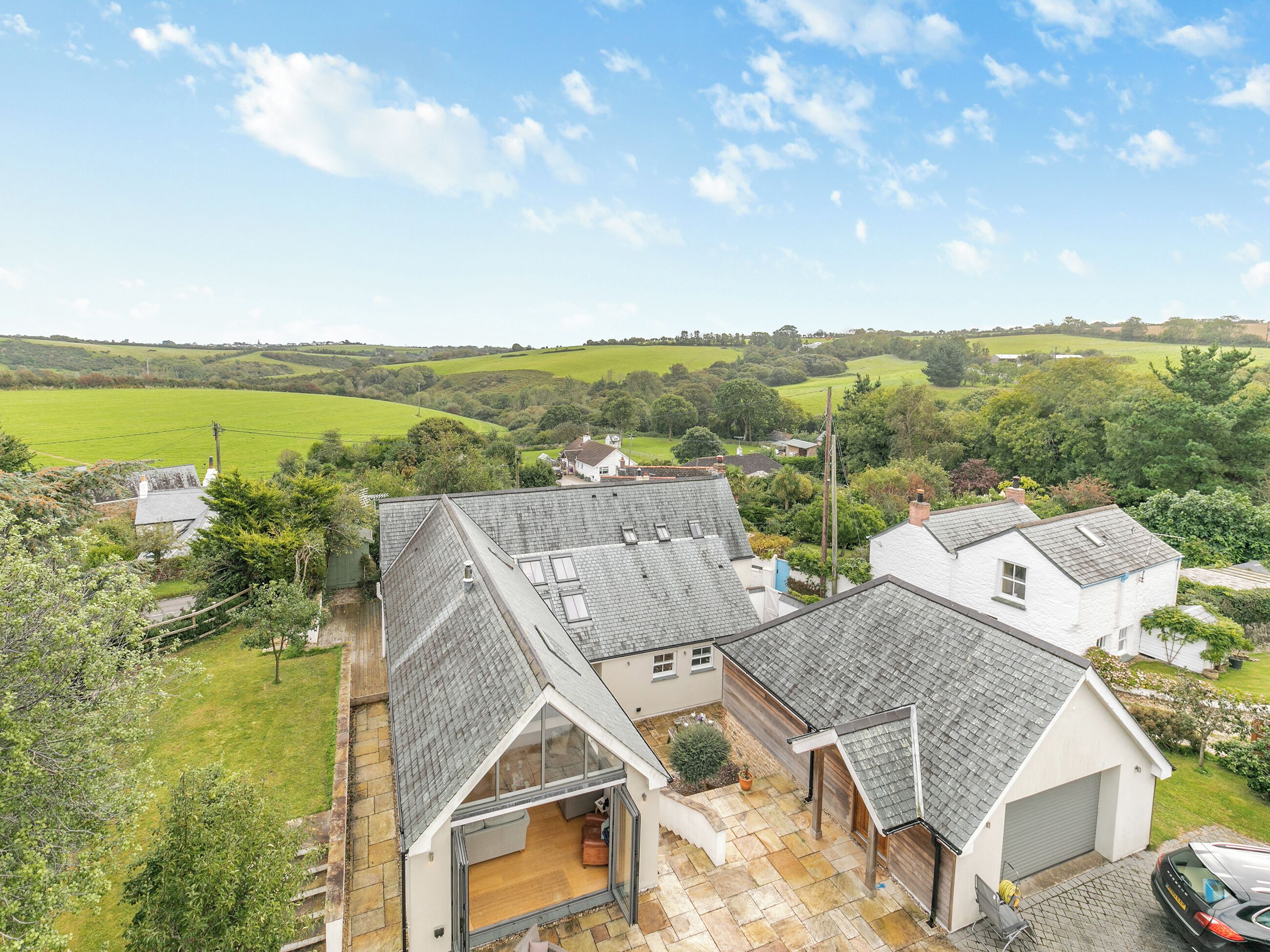 A residential property with a spacious patio, a garage, and a view of the surrounding countryside.