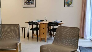Una sala de estar moderna con comedor, que incluye una mesa y sillas de madera, un sofá y un equipo de aire acondicionado en la pared.