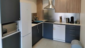 Una cocina compacta con refrigerador, estufa, pileta y muebles de madera.