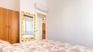 A bedroom with a floral bedspread, wooden wardrobe, and a mirror with a colorful frame. - 3533 Il Giglio Azzurro by Barbarhouse (Salve)