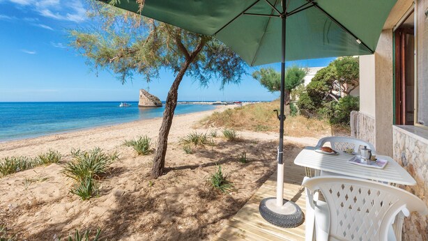 A beachside patio with a table and chairs under a green umbrella, overlooking the sea. - 3533 Il Giglio Azzurro by Barbarhouse (Salve)
